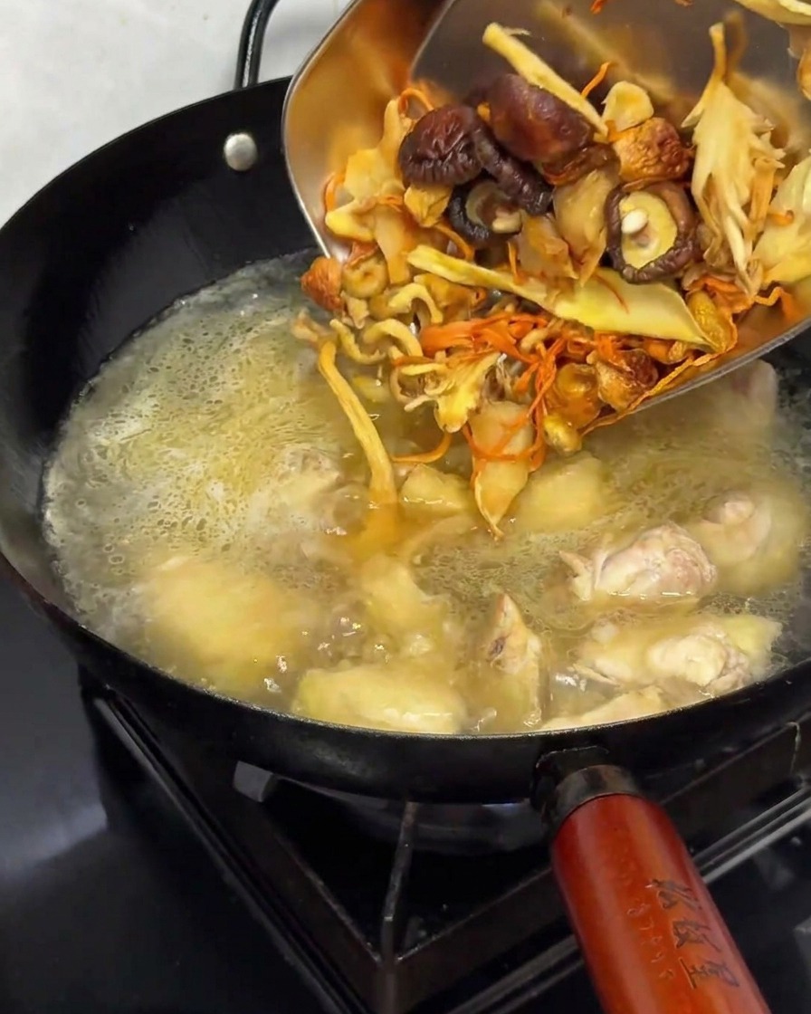 Champignons séchés réhydratés ajoutés dans la marmite avec le poulet et le bouillon.