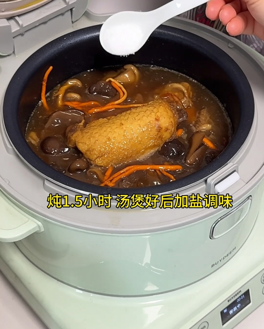 Ajout de sel dans la soupe au poulet prête dans le cuiseur à riz.
