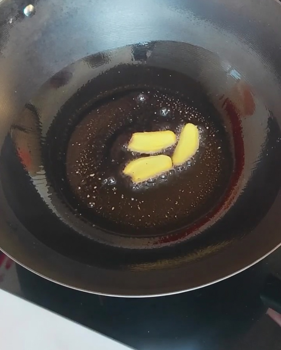 Tranches de gingembre et divers champignons sautés dans un wok chaud.