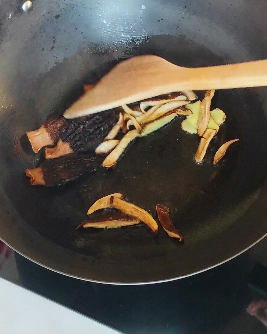 Poulet effiloché mélangé avec des champignons et du gingembre dans un wok.