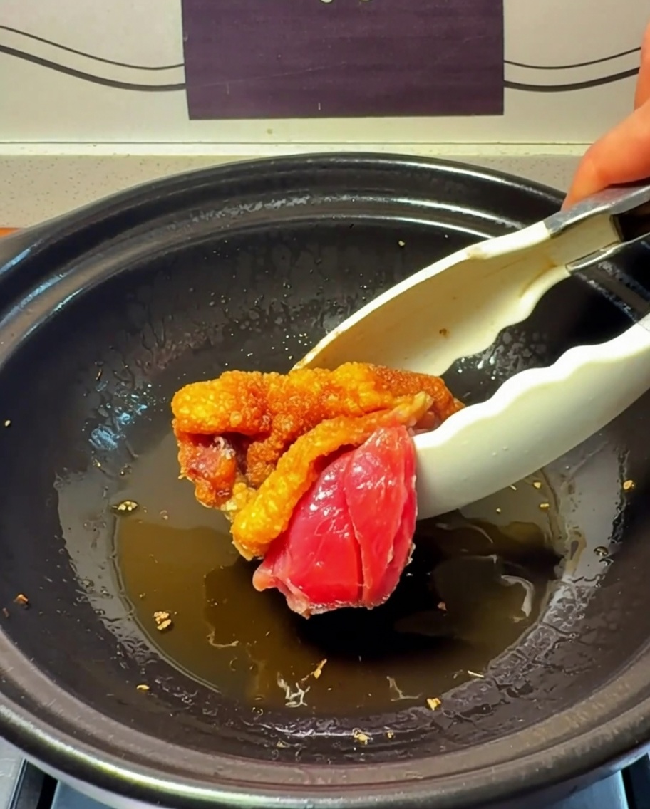 Morceaux de poulet en train de saisir et de dorer dans le pot en argile.