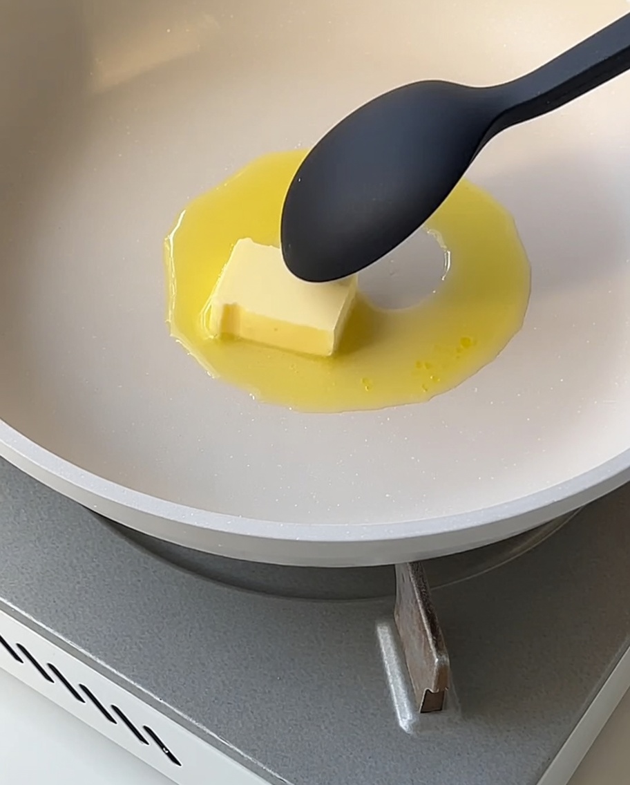 Une sauce blanche lisse qui épaissit dans une poêle, remuée avec une cuillère.