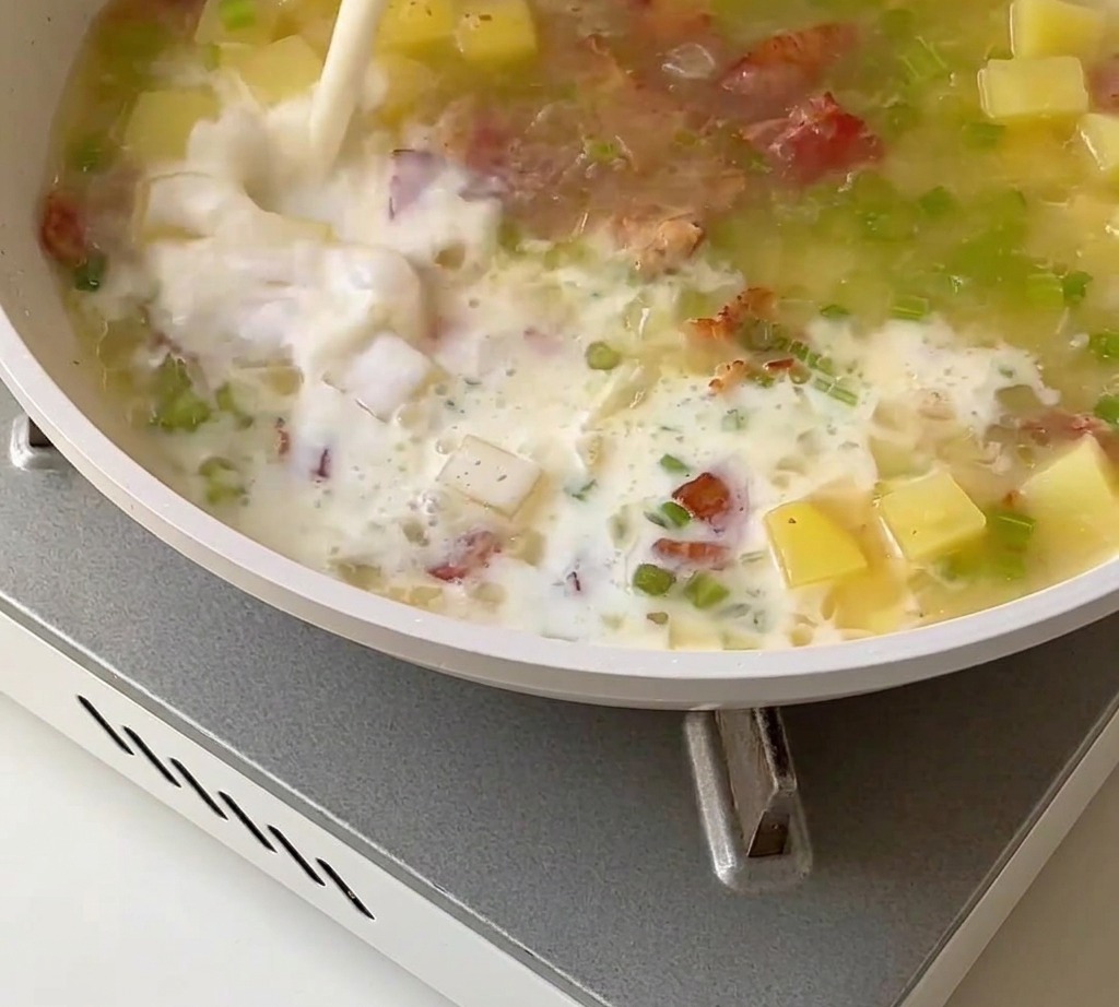 Une base de chaudrée aux palourdes crémeuse mélangée avec du lait, de la crème et de la chair de palourde dans une casserole.