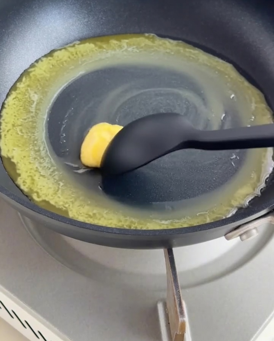 Une poêle contenant du beurre fondu et de la farine mélangés en un roux avec une spatule en silicone.