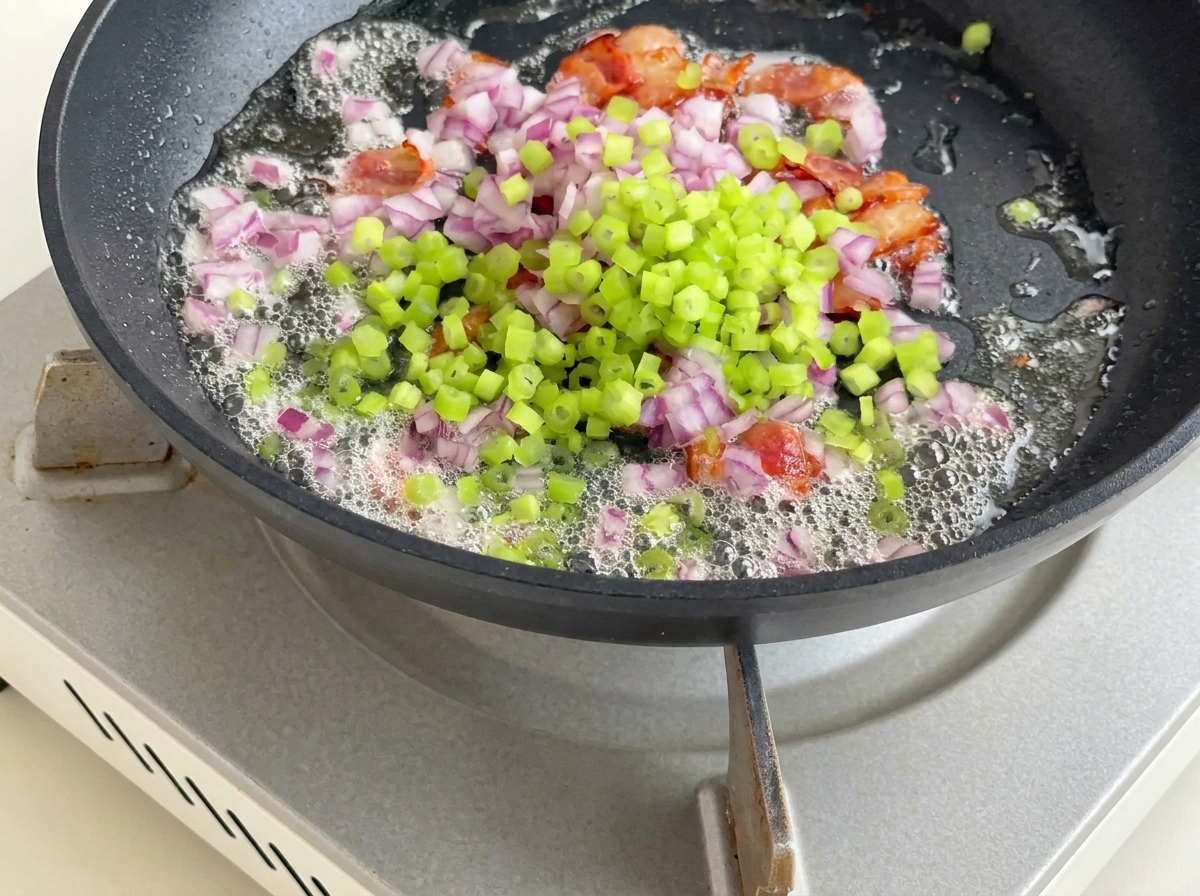 Pommes de terre, céleri et oignon rouge ajoutés à la poêle avec les lardons et le gras.