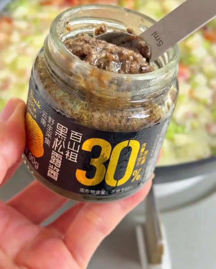 Une cuillerée de pâte de truffe noire ajoutée à la poêle frémissante.