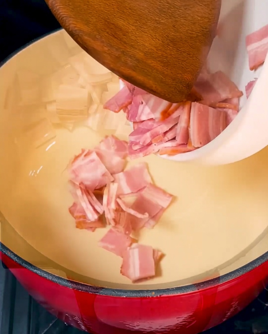 Des morceaux de bacon croustillants dorés grésillant dans une cocotte rouge vibrante.