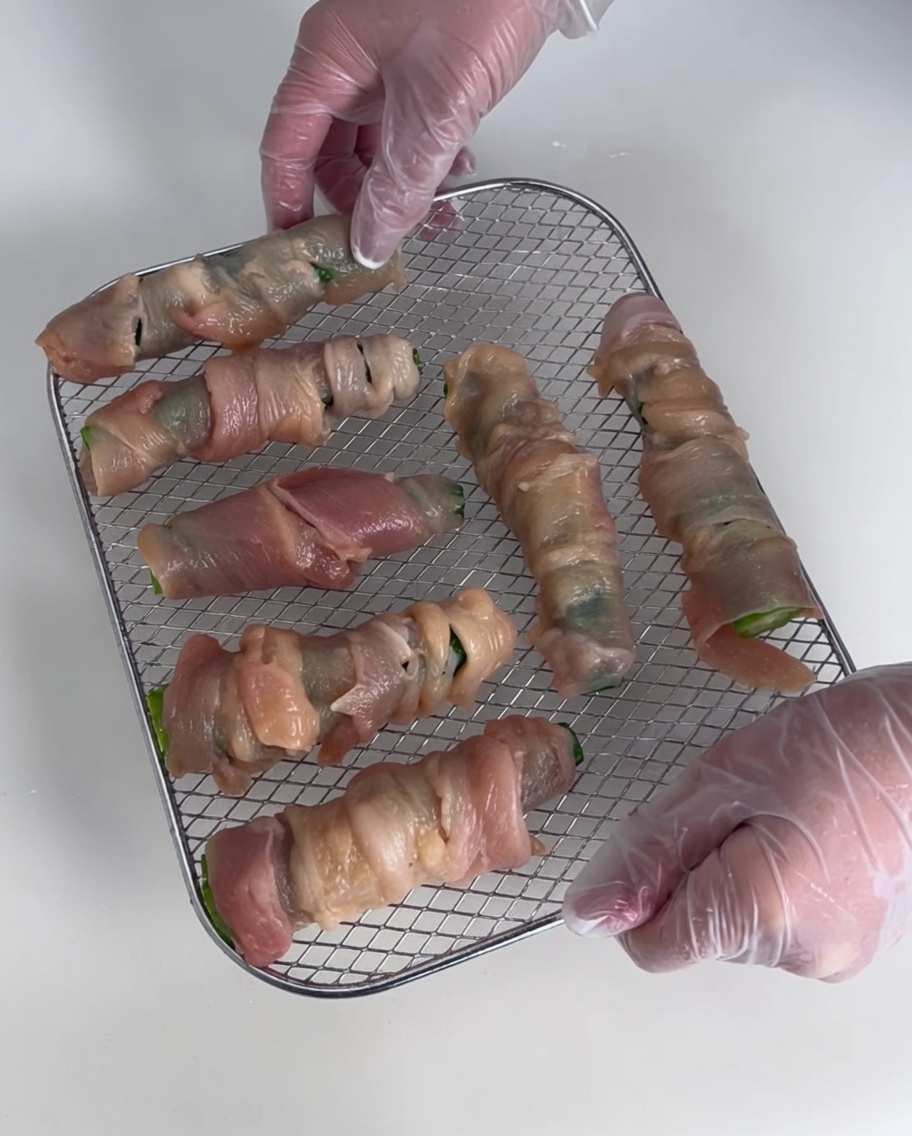Plusieurs wraps de poulet au gombo disposés sur une grille de séchage métallique.