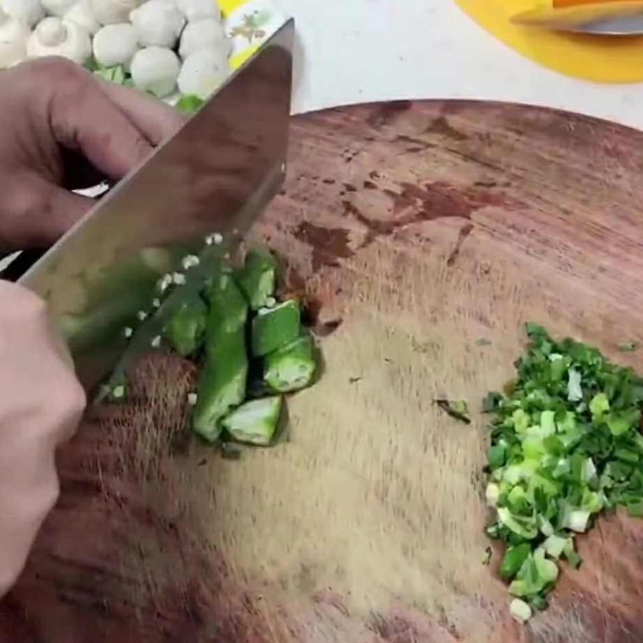 Segments de gombo vert frais coupés sur une planche à découper en bois.