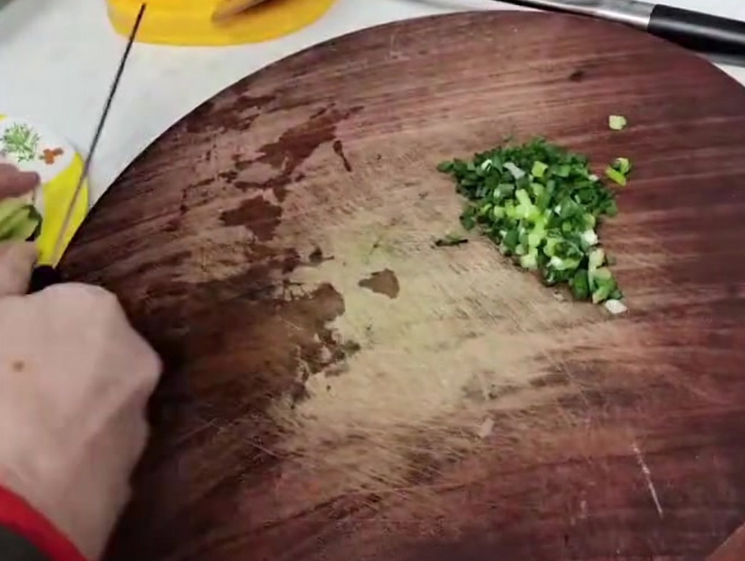 Tiges de pousses de bambou coupées en petits morceaux uniformes sur une planche en bois.