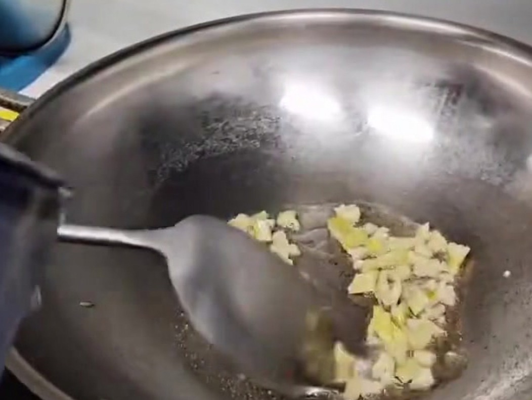 De leau versée dans un wok en métal pour former la base de la soupe aux champignons.