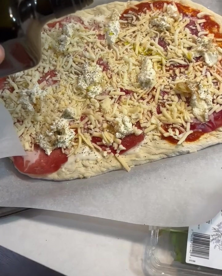 Un léger filet dhuile dolive appliqué sur la pizza assemblée.