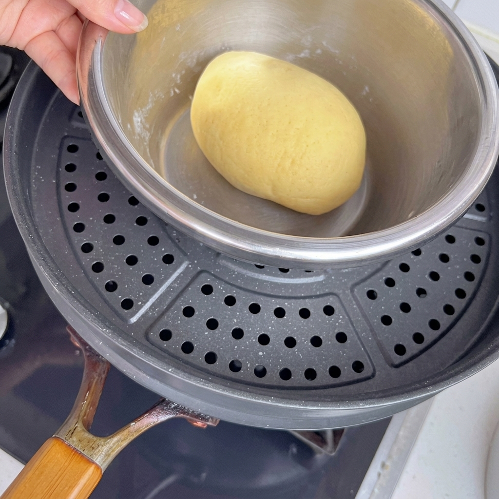 Bol de pâte placé dans une casserole au-dessus deau chaude pour faciliter la pousse.