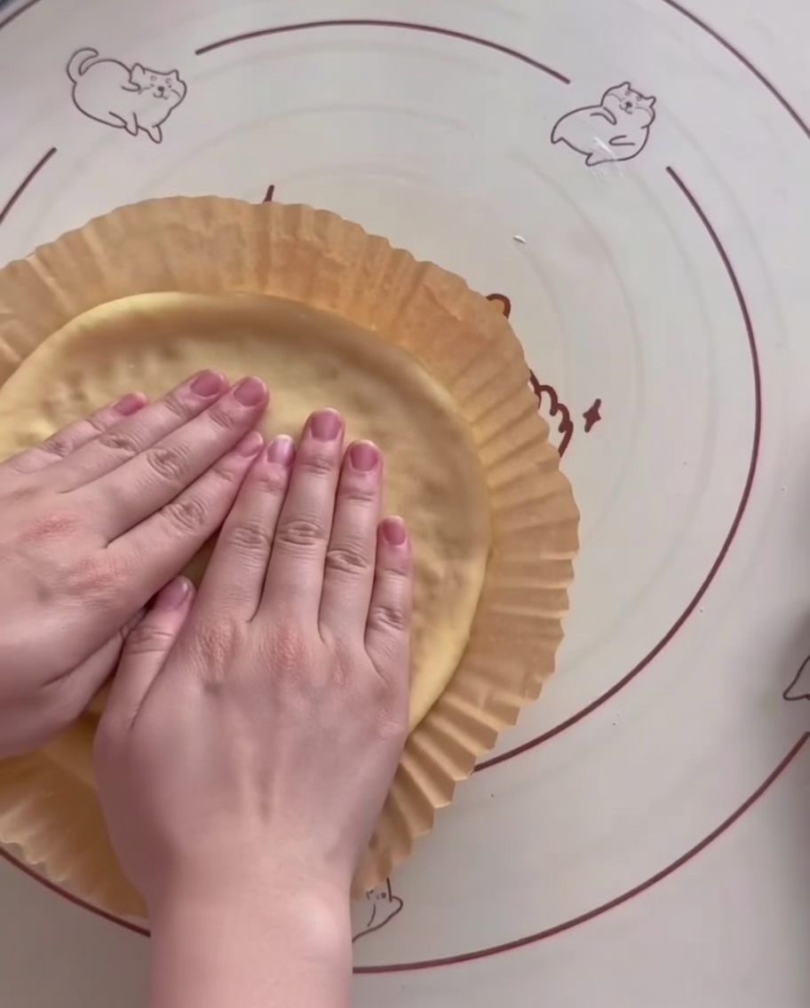 Pâte façonnée dans un moule en papier pour friteuse avec des bords surélevés formés à la main.
