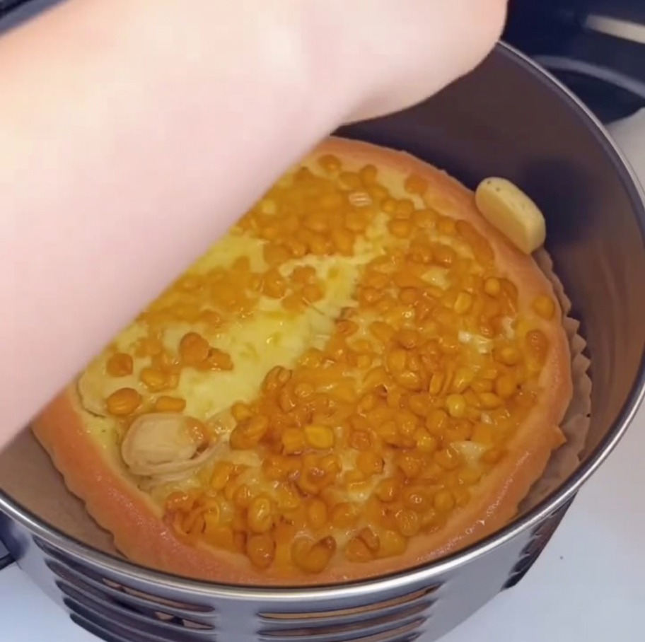 Une main utilisant un petit pinceau pour appliquer de lhuile sur le bord doré dune pizza partiellement cuite dans la friteuse.
