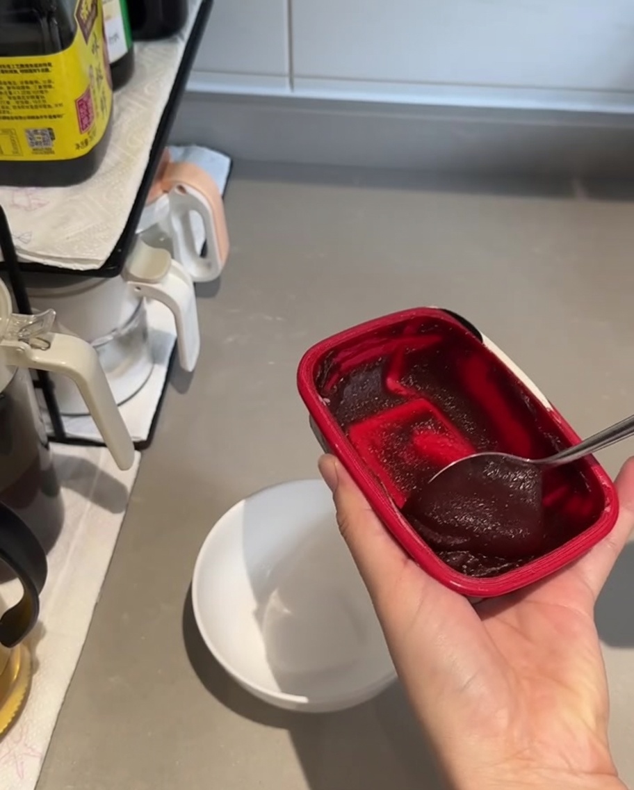 Un petit bol blanc contenant une grosse cuillerée de pâte gochujang rouge foncé et de la sauce soja.