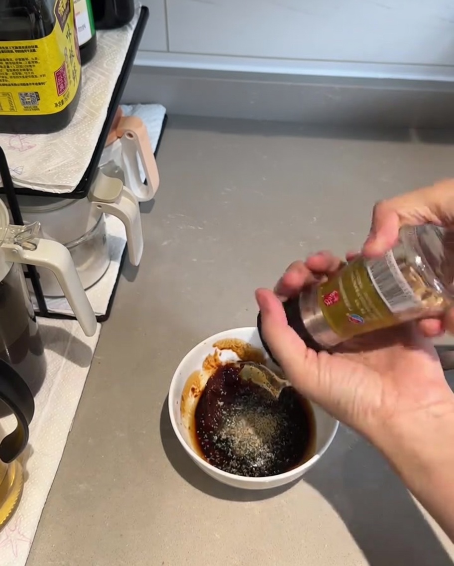 Une cuillère mélangeant les ingrédients de la sauce dans un bol blanc.