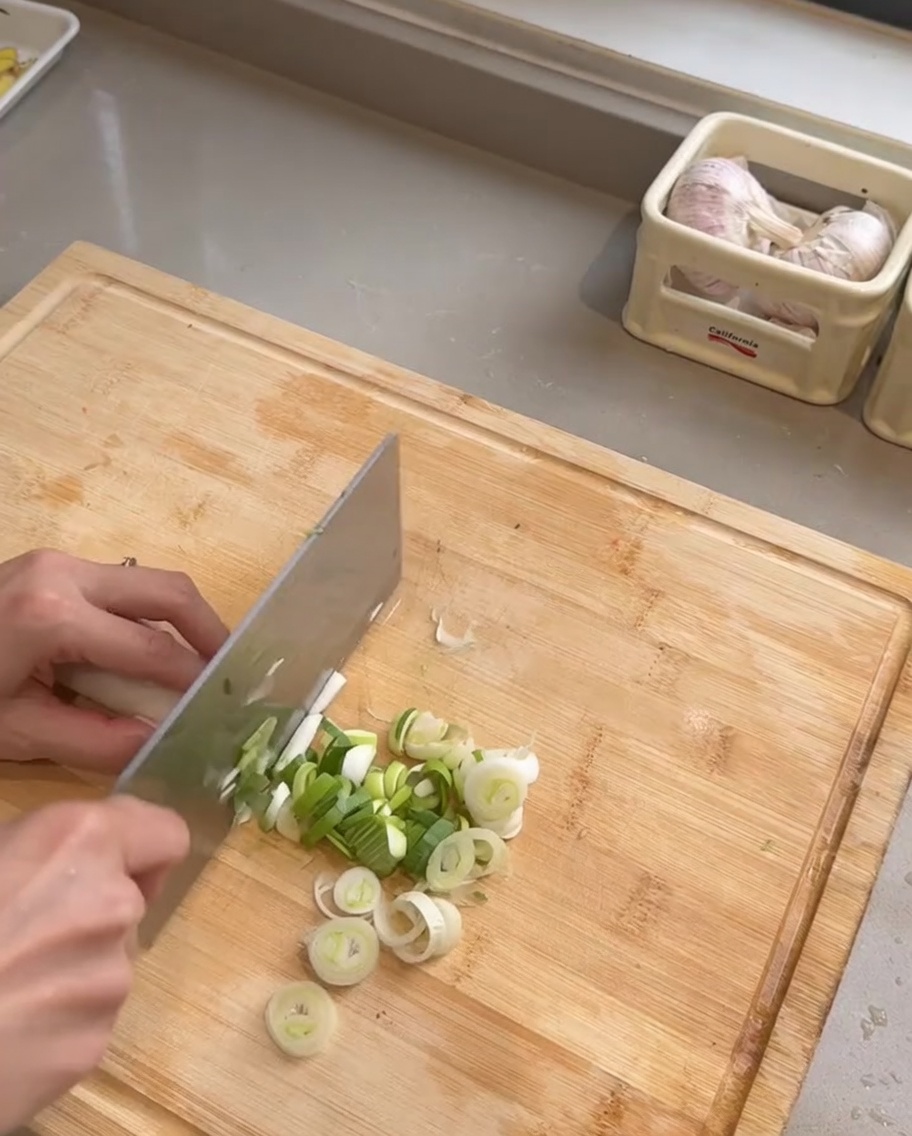 Tranches de porc, lamelles doignon violet et ail haché cuisant dans une poêle chaude huilée.