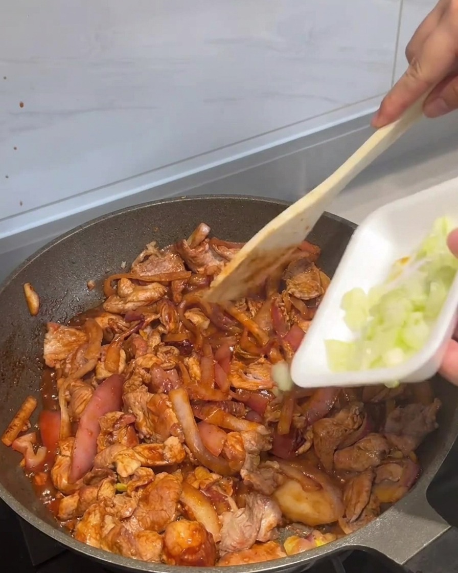 Oignons verts ajoutés à la poêle de porc sauté.