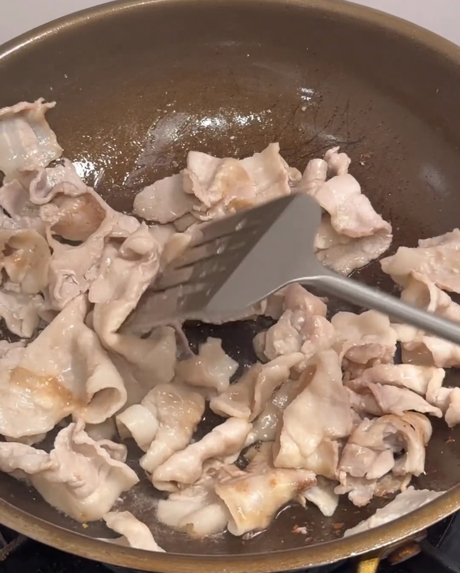 Oignons, cives et piment ajoutés à la viande dans la poêle.