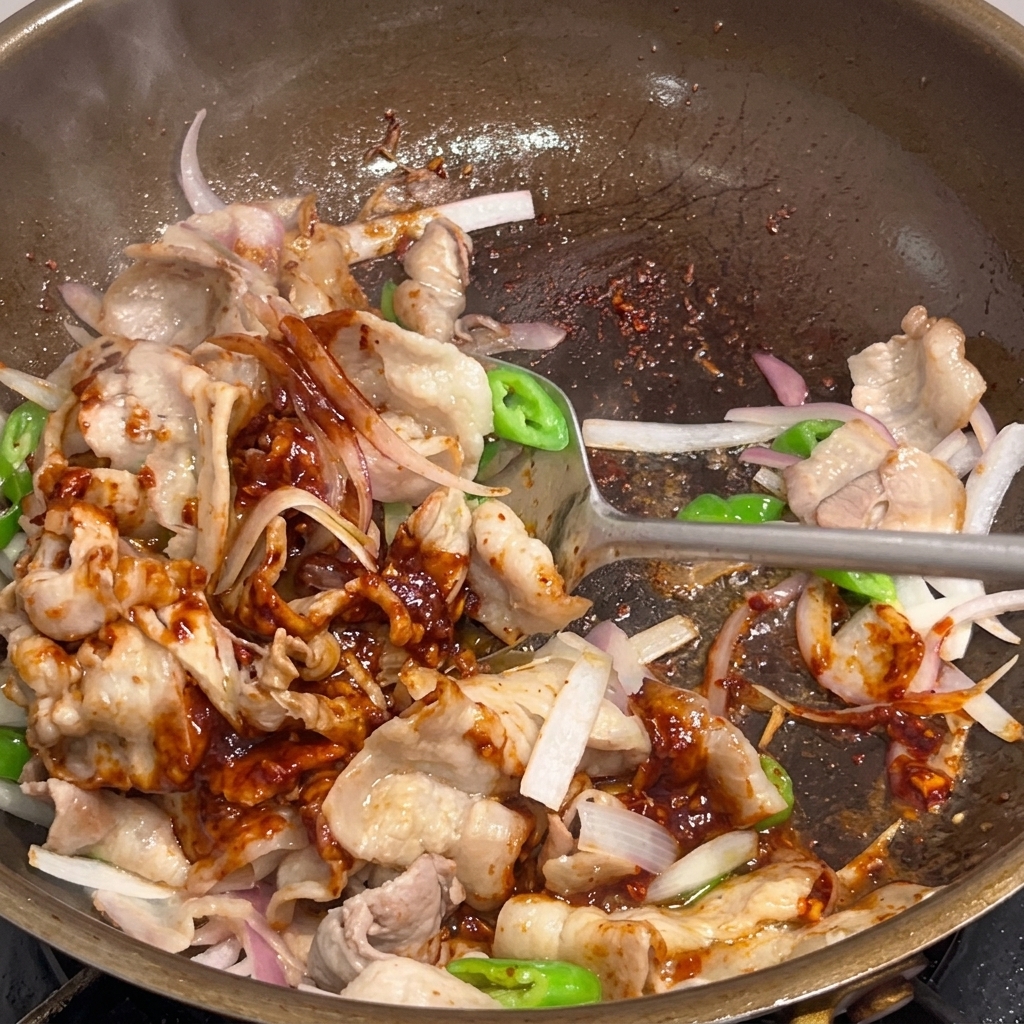 Le porc épicé mélangé dans la poêle jusquà être parfaitement nappé de sauce.