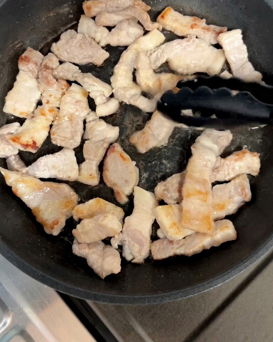 Morceaux de poitrine de porc retournés dans la poêle jusquà obtenir une couleur dorée.