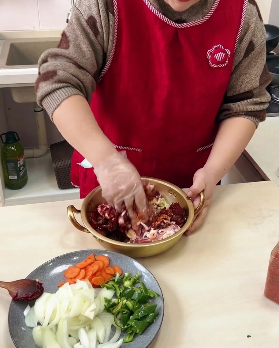 Mains mélangeant le porc mariné dans un bol en métal, mélangeant tous les ingrédients.