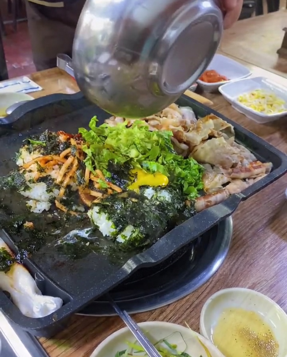 Kimchi et oignons verts ajoutés sur la plaque avec le riz et le porc.