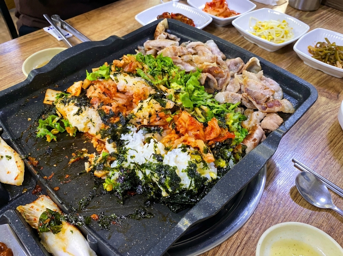 Riz, porc et légumes mélangés sur la plaque du gril avec des spatules en bois.