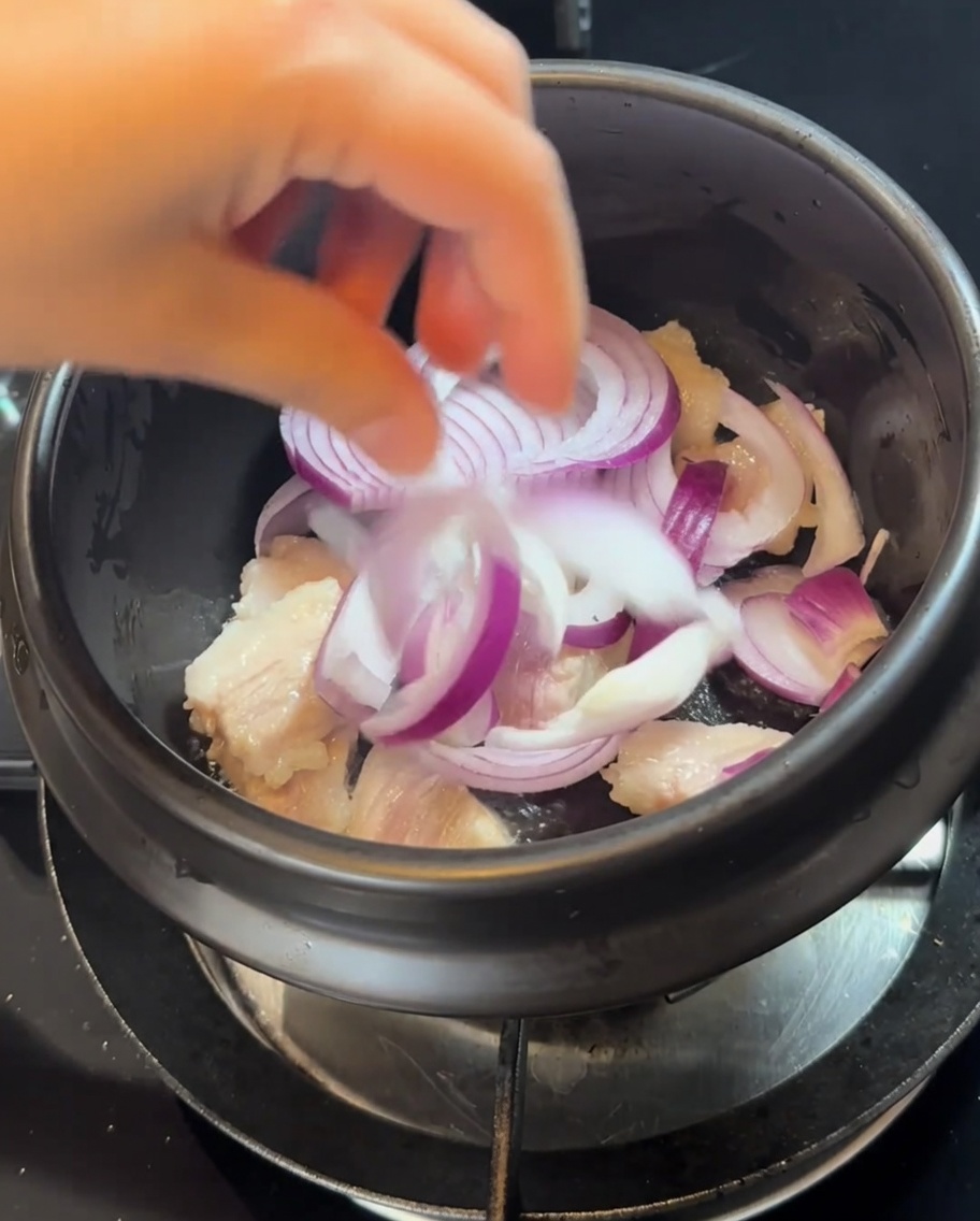 Tranches doignon rouge ajoutées au pot avec le porc doré.