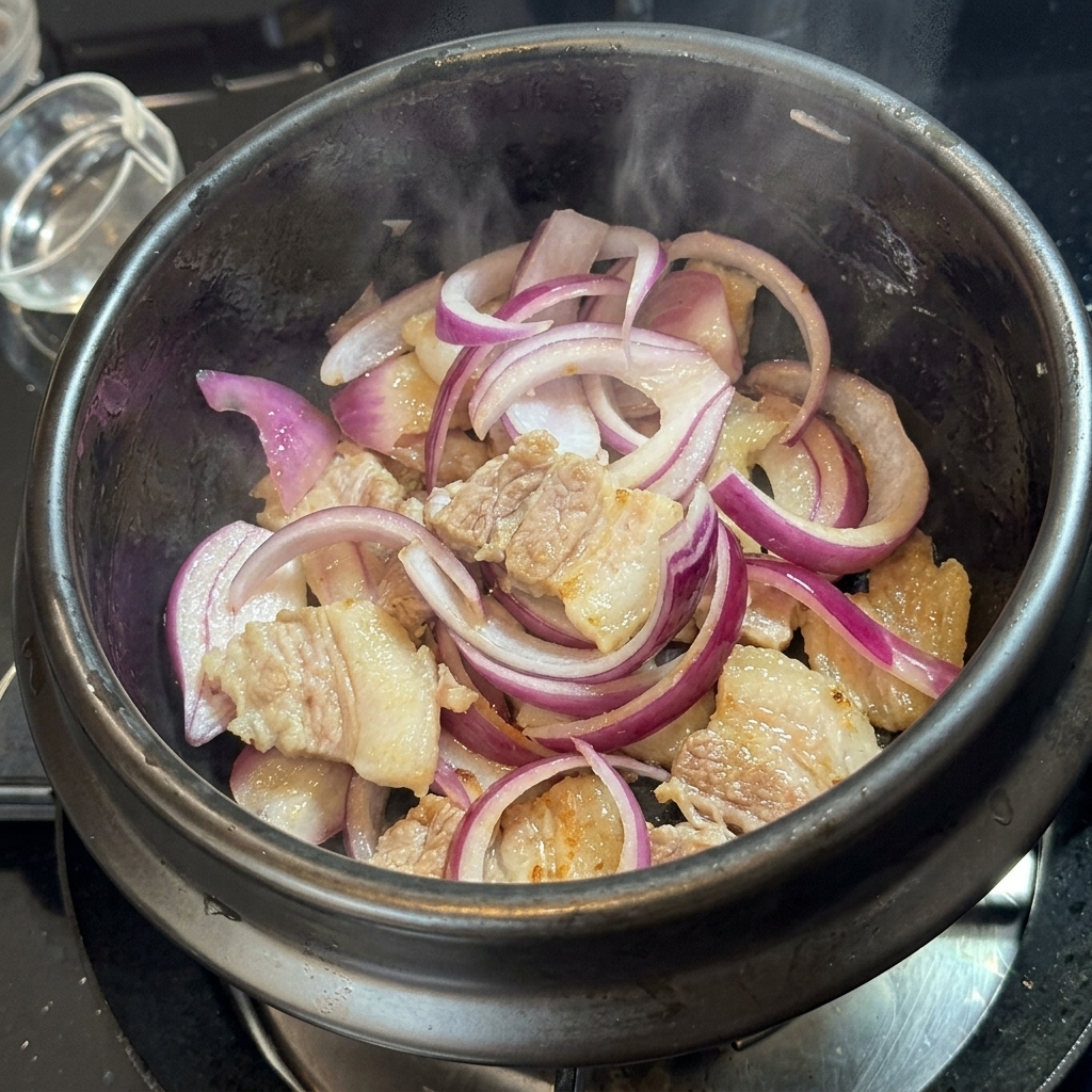 Kimchi mélangé au porc et aux oignons dans le pot en pierre.