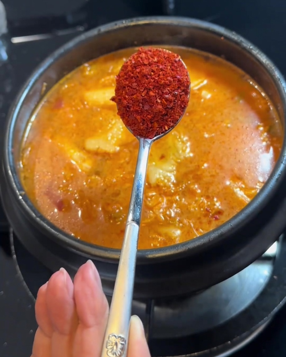 Piment en poudre ajouté au ragoût à laide dune cuillère.