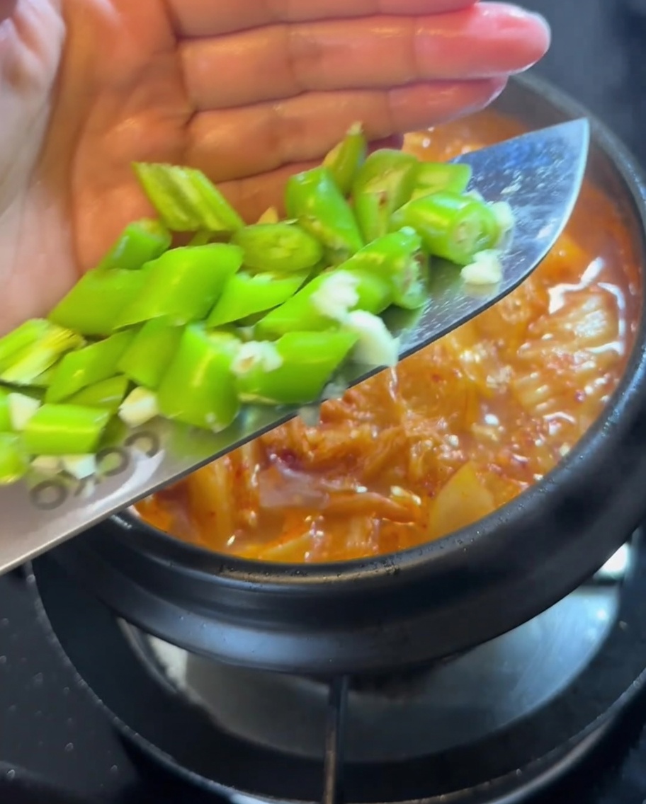 Morceaux de piment vert frais ajoutés dans le ragoût bouillonnant.