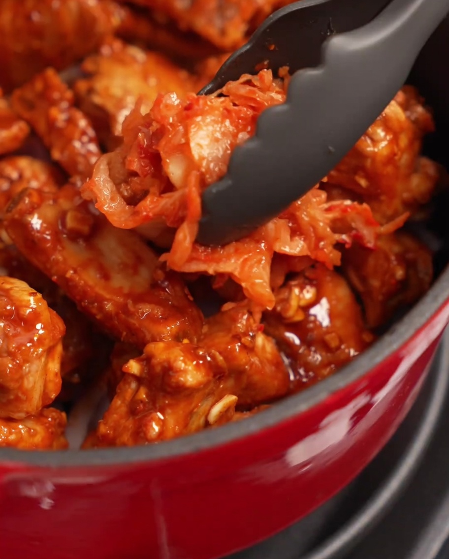 Généreuse portion de kimchi rouge assaisonné déposée sur les travers de porc dans la cocotte.