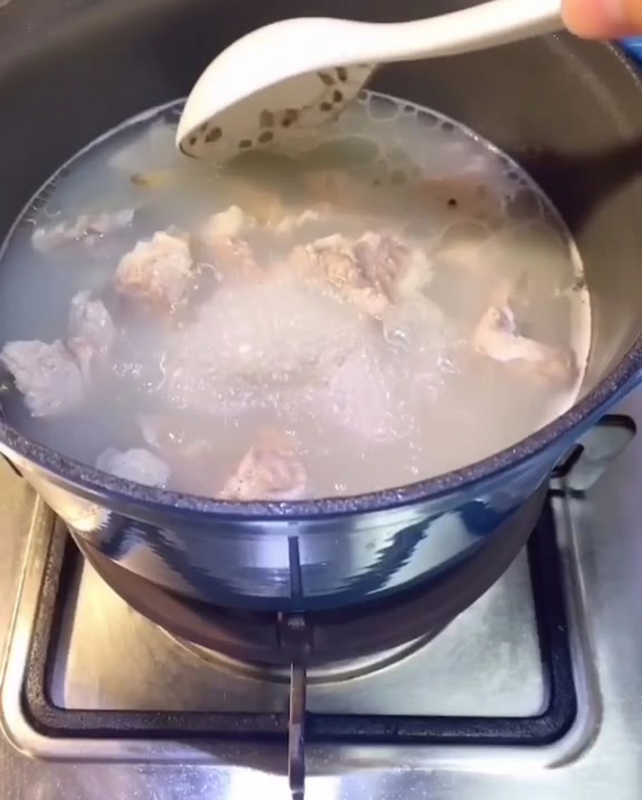 Travers de porc cuisant dans une casserole deau sur la cuisinière, un bouillon clair commence à se former.