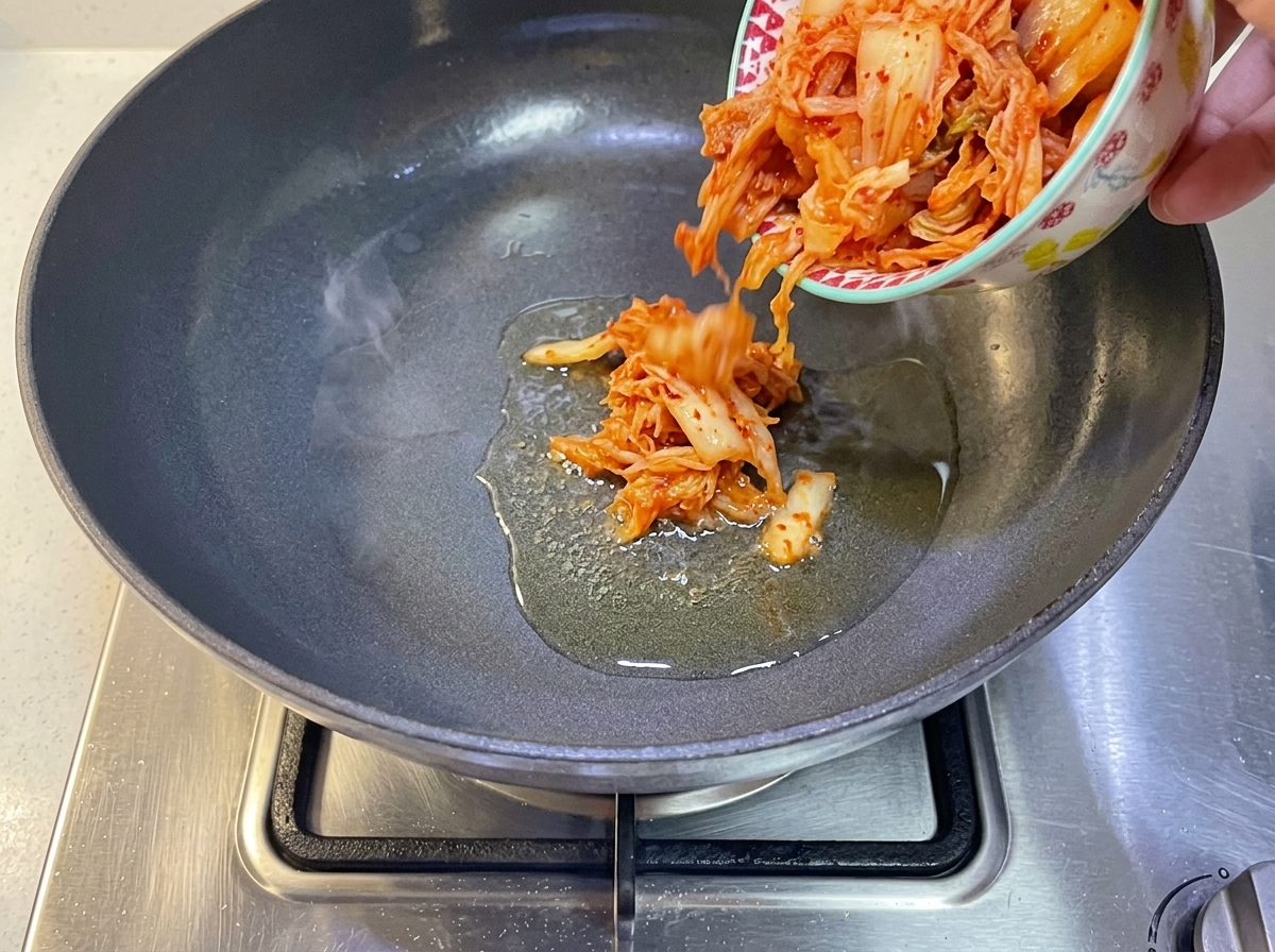 Du kimchi coréen versé dans une poêle avec de lhuile chaude.
