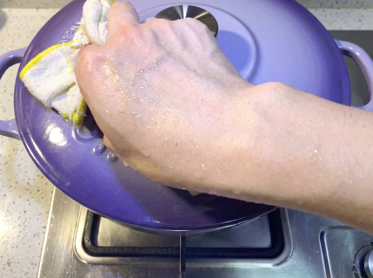 Main plaçant un couvercle violet sur la casserole pour couvrir le ragoût.
