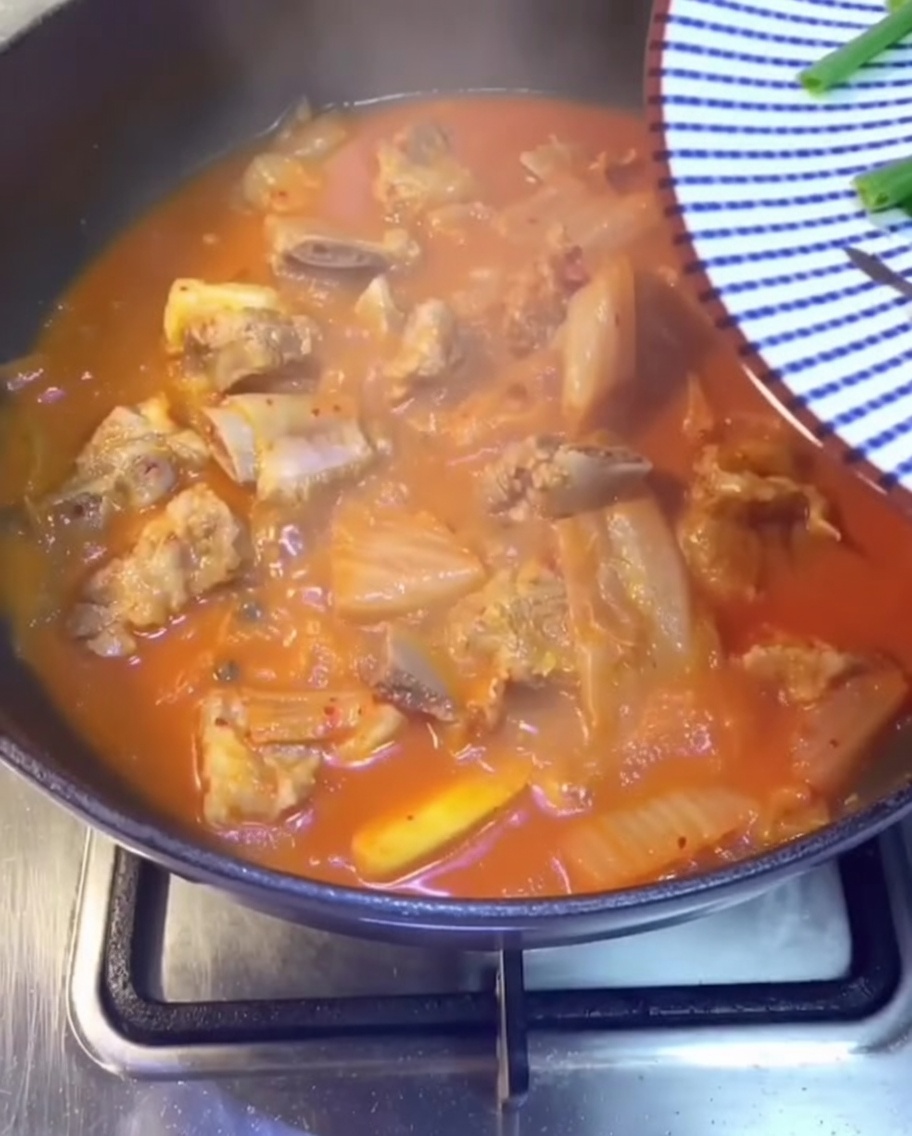 Gros plan doignons verts frais, de coriandre et de piments verts tranchés saupoudrés sur le ragoût.