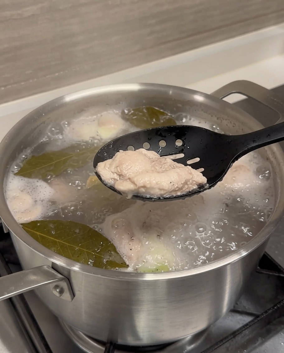 Un travers de porc blanchi soulevé de leau bouillante avec des pinces noires.