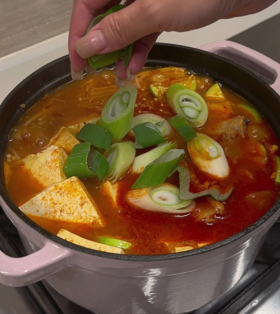 Oignons verts et piments frais saupoudrés sur une marmite de soupe finie.