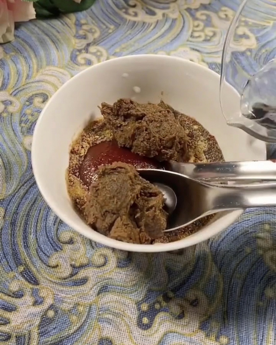 Gros plan sur un bol blanc contenant un mélange de pâte de piment coréenne et de pâte de soja, avec de leau fraîche versée pour diluer lassaisonnement.