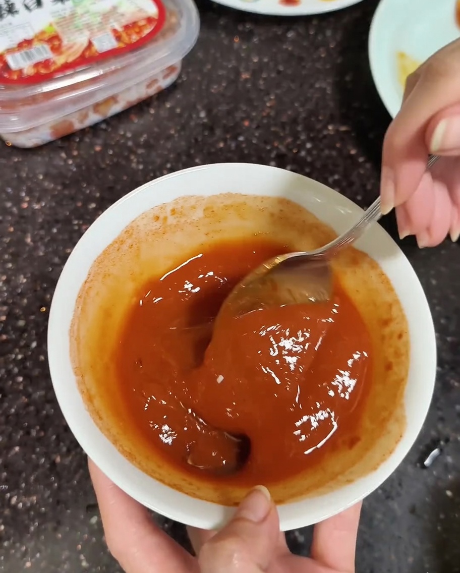 Gros plan dune cuillère mélangeant les pâtes coréennes avec un peu deau jusquà obtenir une consistance lisse.