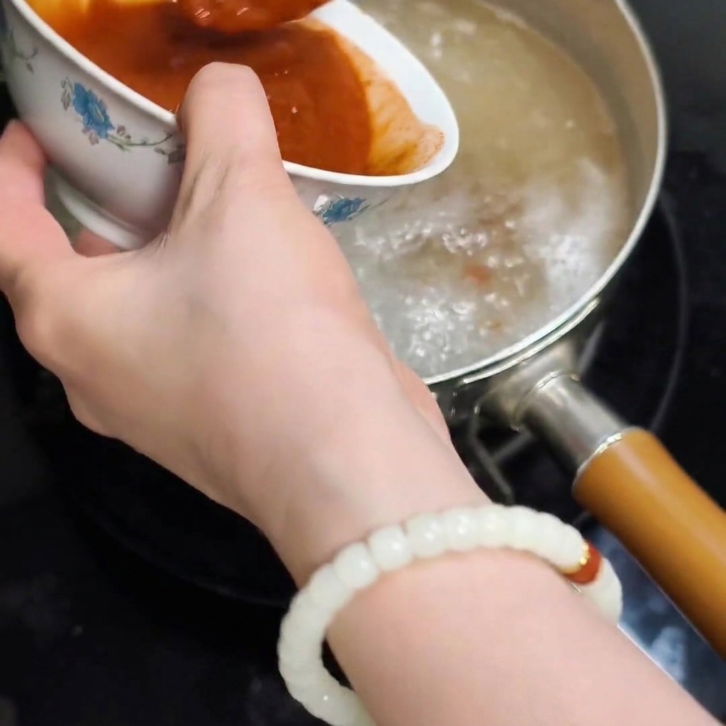 Le mélange de pâtes dissoutes versé depuis un bol dans leau bouillante de la marmite.