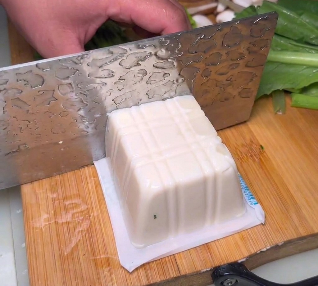 Blocs de tofu soyeux coupés en morceaux sur une planche.