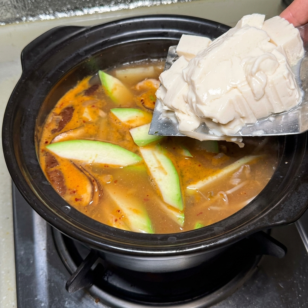 Blocs de tofu soyeux délicatement déposés dans le pot.