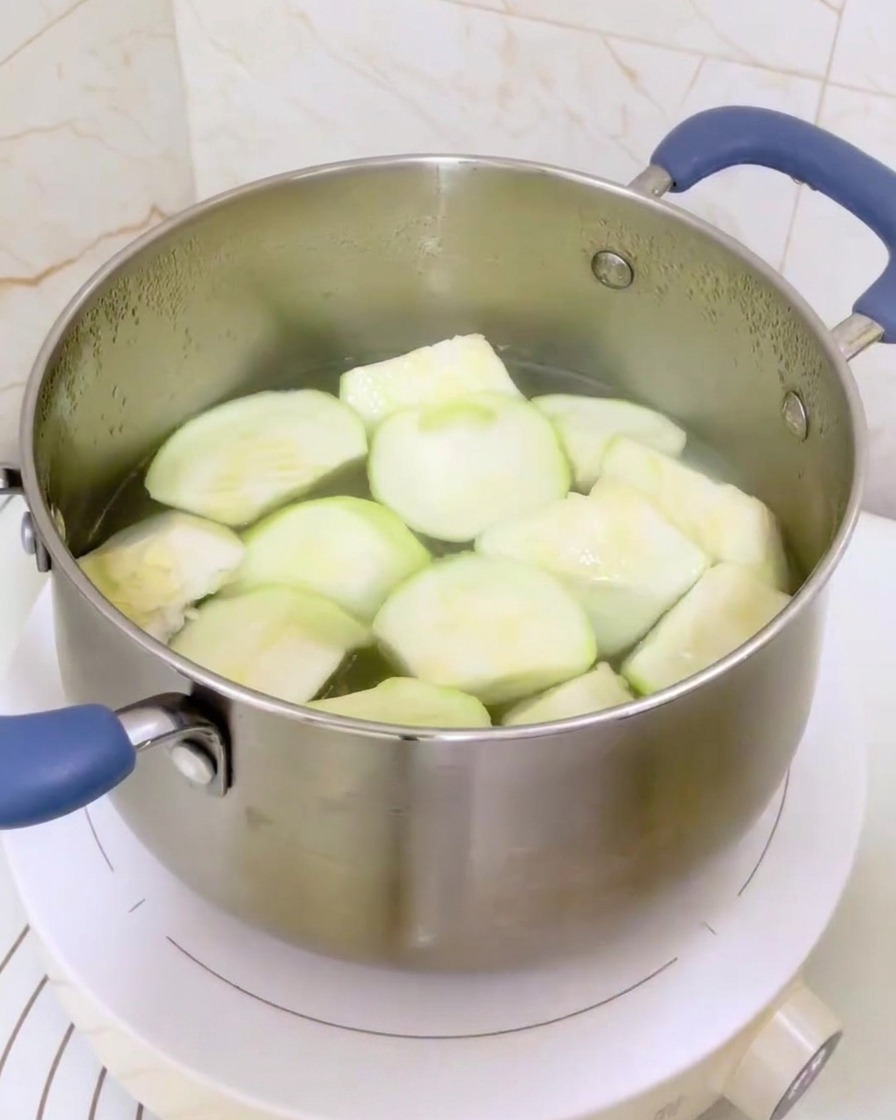 Une casserole en acier inoxydable couverte dun couvercle en verre posée sur une plaque à induction.