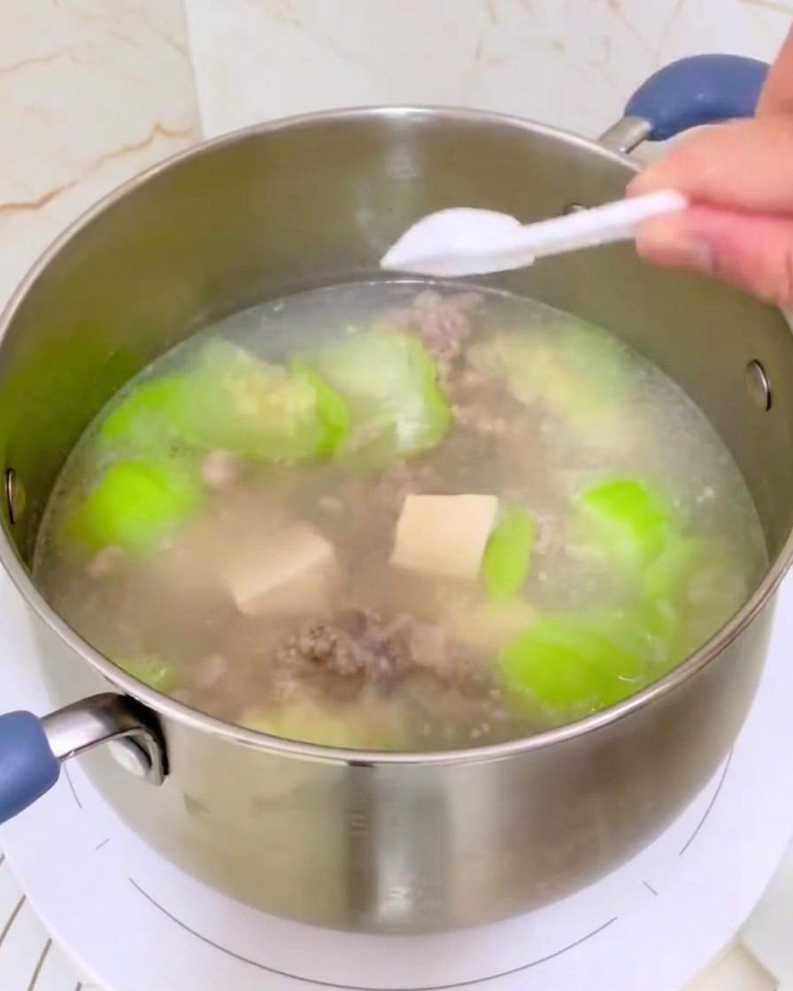 Assaisonnements saupoudrés dune petite cuillère blanche dans la casserole de soupe terminée.
