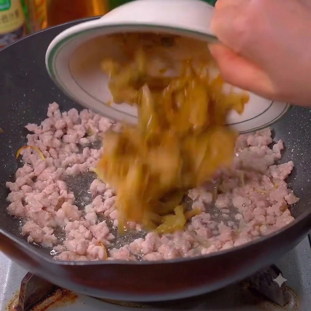 Moutardes marinées versées dans le wok avec le porc.