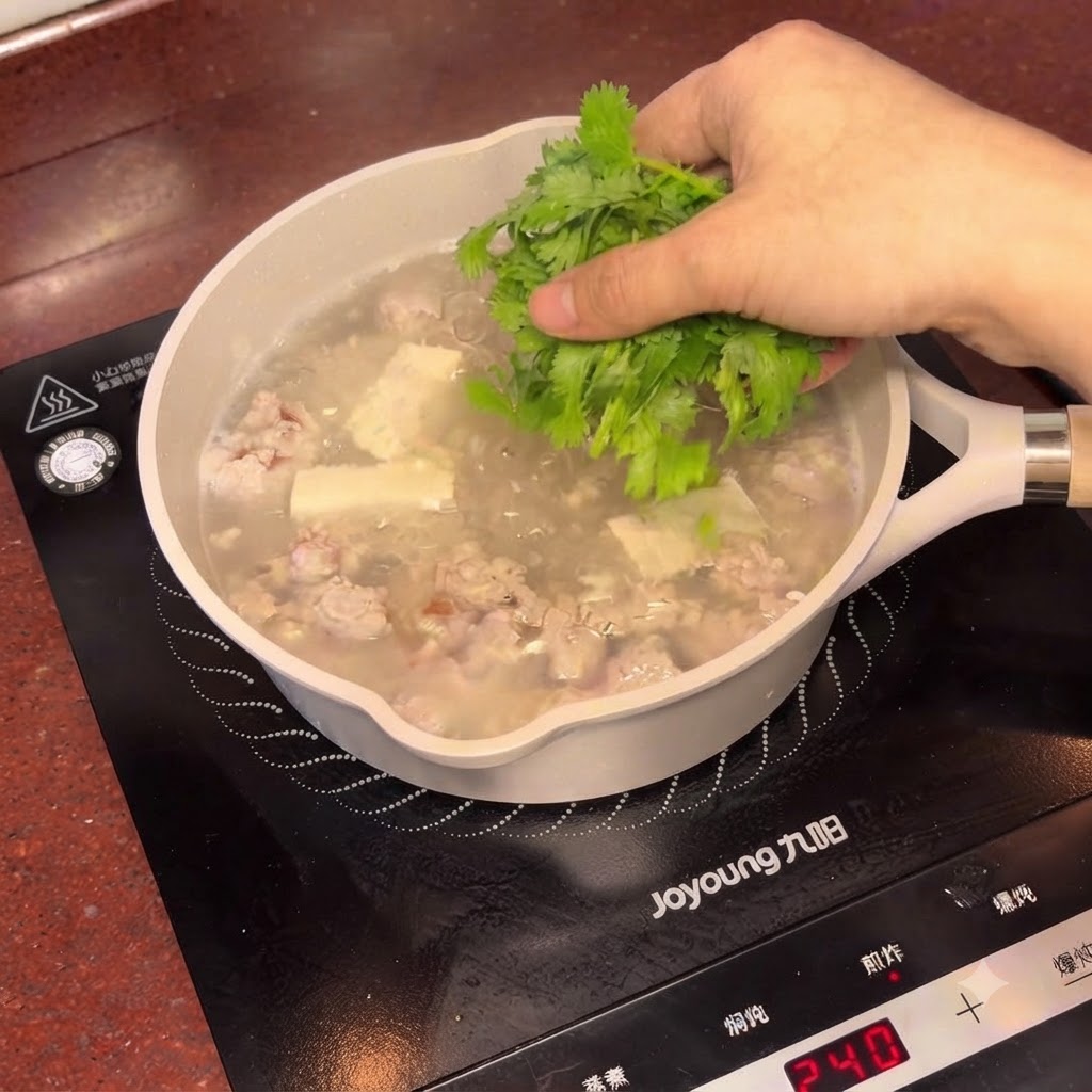 Coriandre fraîche hachée saupoudrée sur la casserole fumante de soupe au tofu et prunes salées.