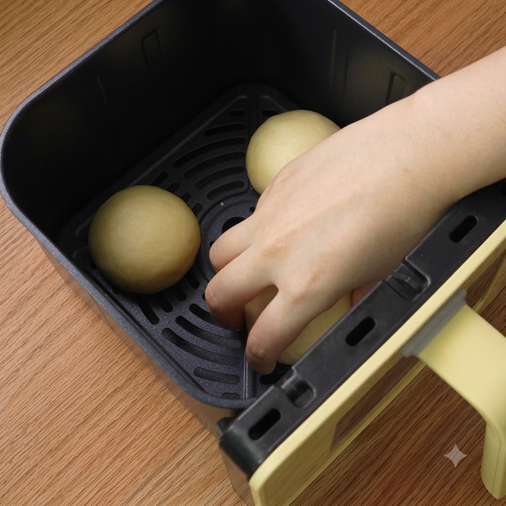 Trois boules de pâte façonnées et soigneusement disposées dans le panier de la friteuse sans huile.
